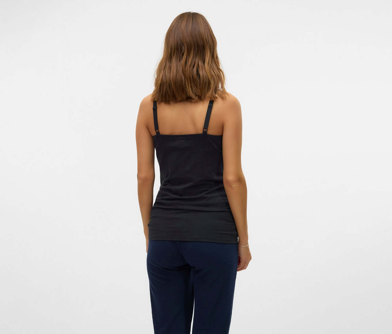 Frau von hinten mit schwarzem MAMALICIOUS 2er Pack Spaghettiträger »MLKERRIE« und blauer Hose vor weißem Hintergrund.