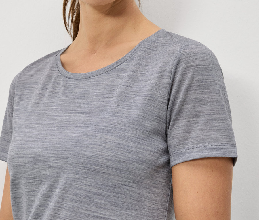 Nahaufnahme einer Frau, die ein meliertes, graues, kurzärmeliges T-Shirt trägt.