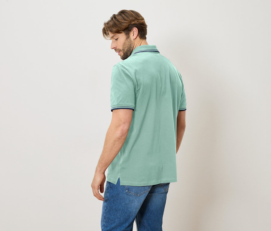 Mann von hinten, trägt hellblaues Poloshirt mit Jeans.