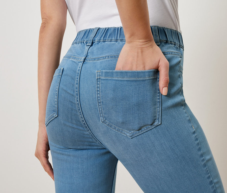 Frau mit Hand in der Gesäßtasche einer hellblauen Jeans.