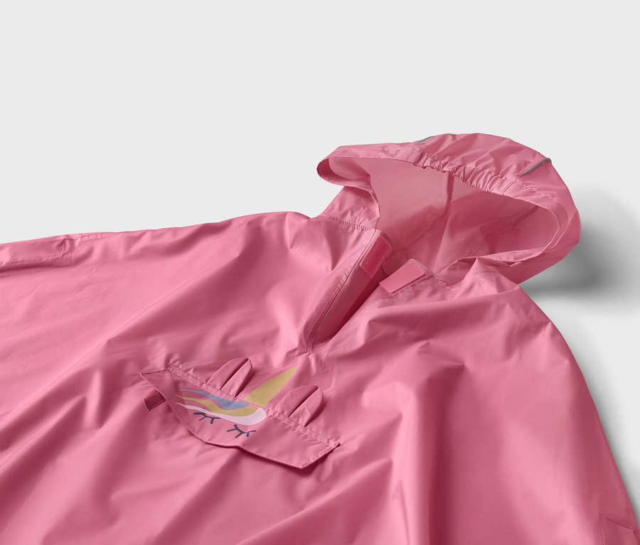 Nahaufnahme eines rosafarbenen Ponchos mit Kapuze und Einhorn-Applikation auf der Tasche.