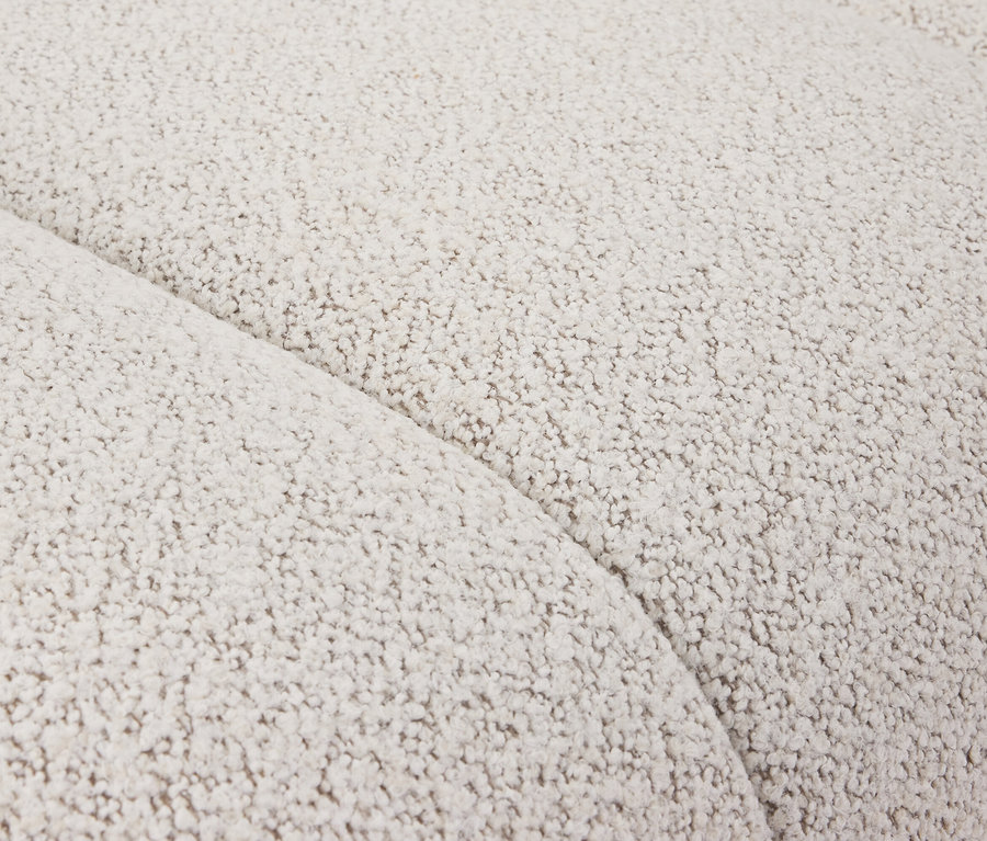 Nahaufnahme eines cremefarbenen Sofas mit Bouclé-Stoff und einer sanften Kurve.