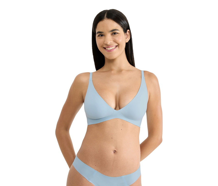 Frau mit dunklen Haaren trägt einen hellblauen BH und passende Unterwäsche.