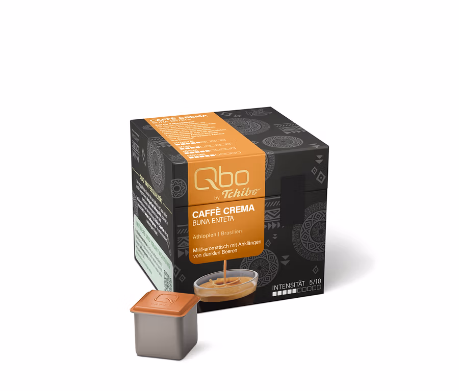 Schwarze Qbo Caffè BUNA ENTETA Kapselpackung mit orangefarbenem Band, daneben eine Kapsel und ein Schälchen mit Kaffeestrahl.