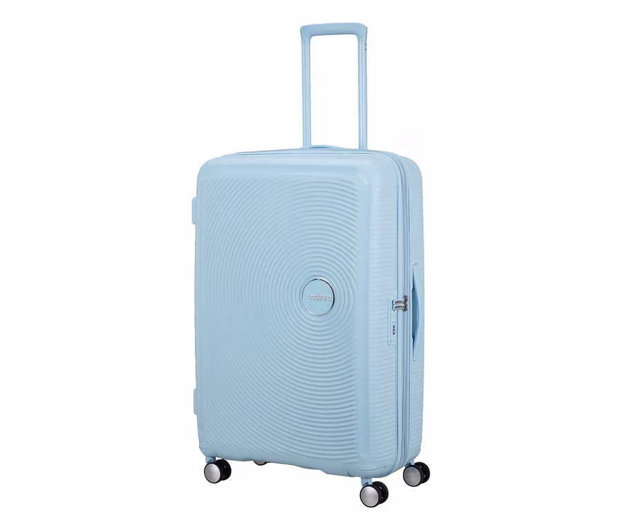 Großer American Tourister Soundbox Hartschalen-Koffer in Pastellblau mit ausgefahrenem Griff, vier Rollen und konzentrischen Kreismustern.