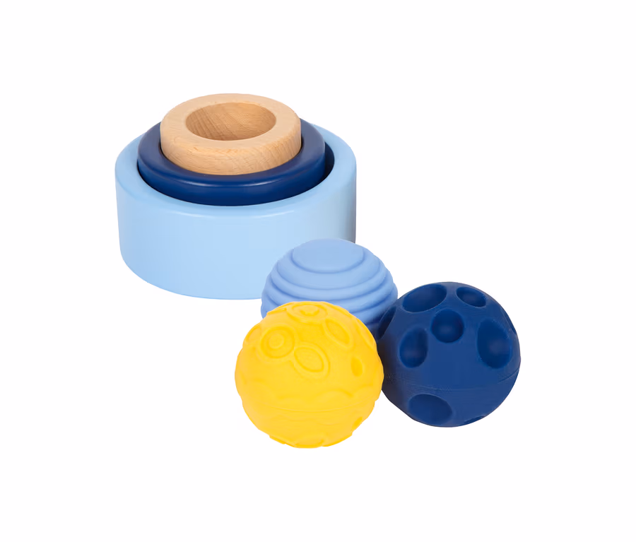Eine small foot Baby-Box, 10–12 Monate, bestehend aus einem Stapelturm mit drei Ringen in Hellblau, Dunkelblau und Naturholz sowie drei strukturierten Bällen in Gelb, Hellblau und Dunkelblau.