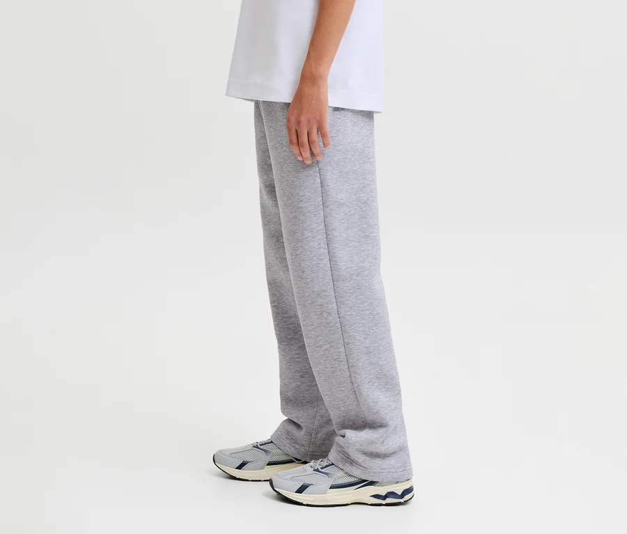 Eine Person trägt graue Jack&Jones Bradley Sweatpants und Turnschuhe.