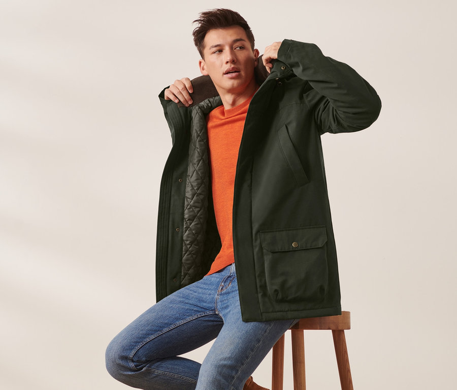 Mann sitzt auf Hocker und trägt Jacke.