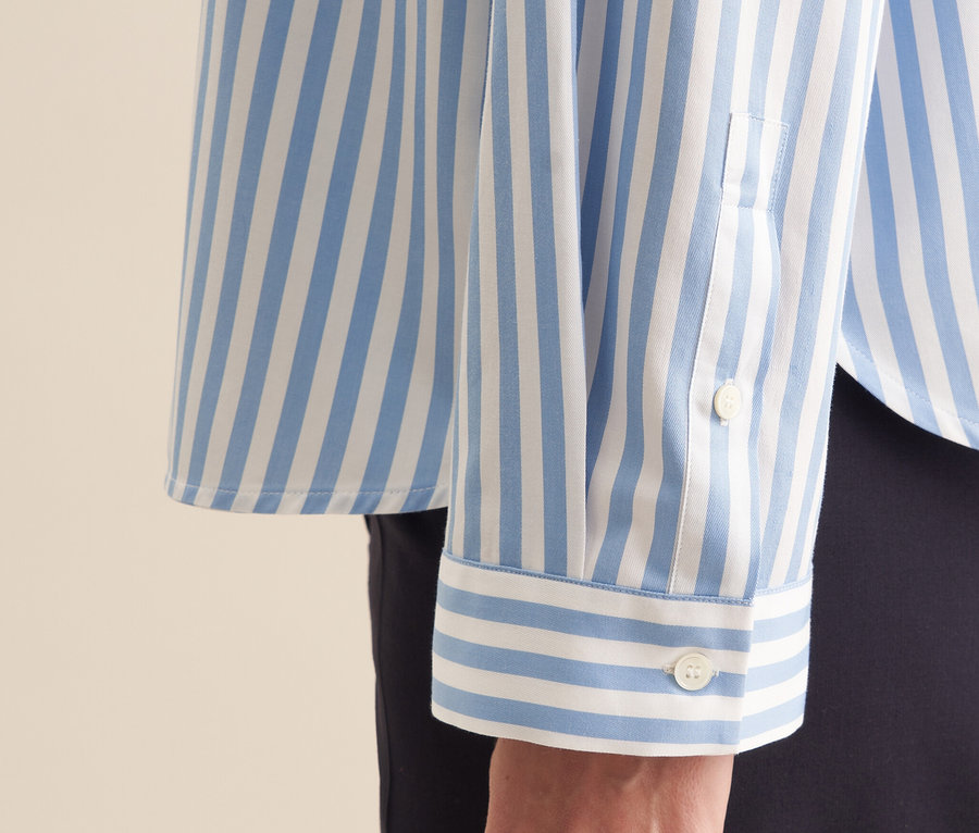 Detail einer blauen Seidensticker Oversize Hemdbluse mit weißen Streifen am Arm einer Frau.