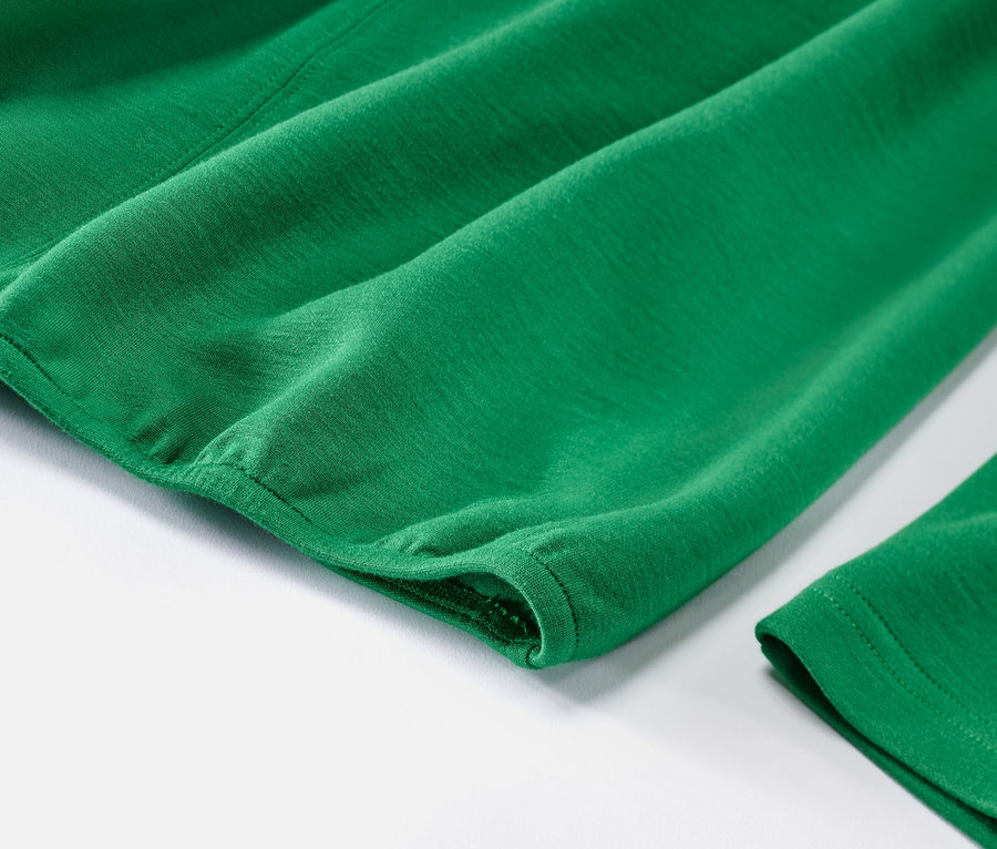 Detailansicht eines grünen Blusenshirts aus Modal-Mix auf weißem Hintergrund.