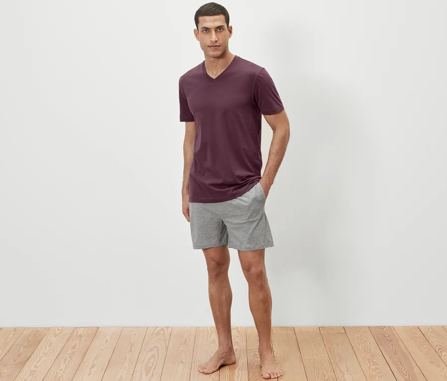 Mann steht in Shorty-Pyjama.
