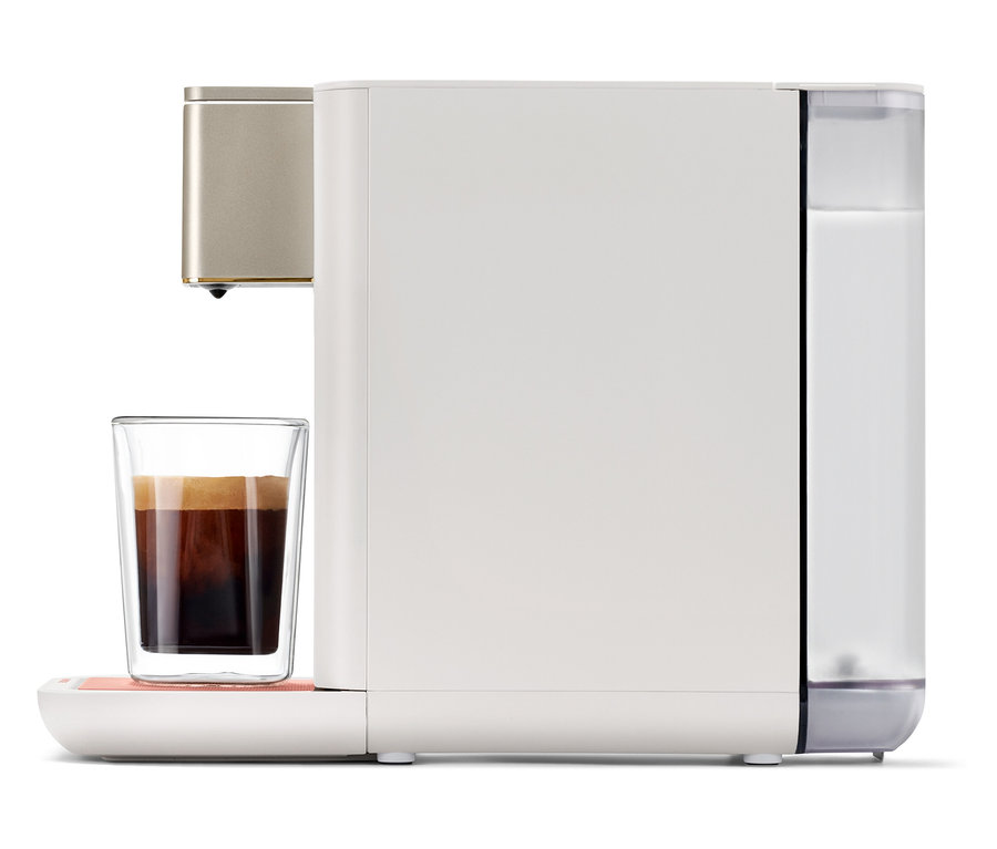 Qbo ICONIC x Pantone Special Edition Muted Clay Kaffeemaschine füllt ein Glas mit Kaffee.