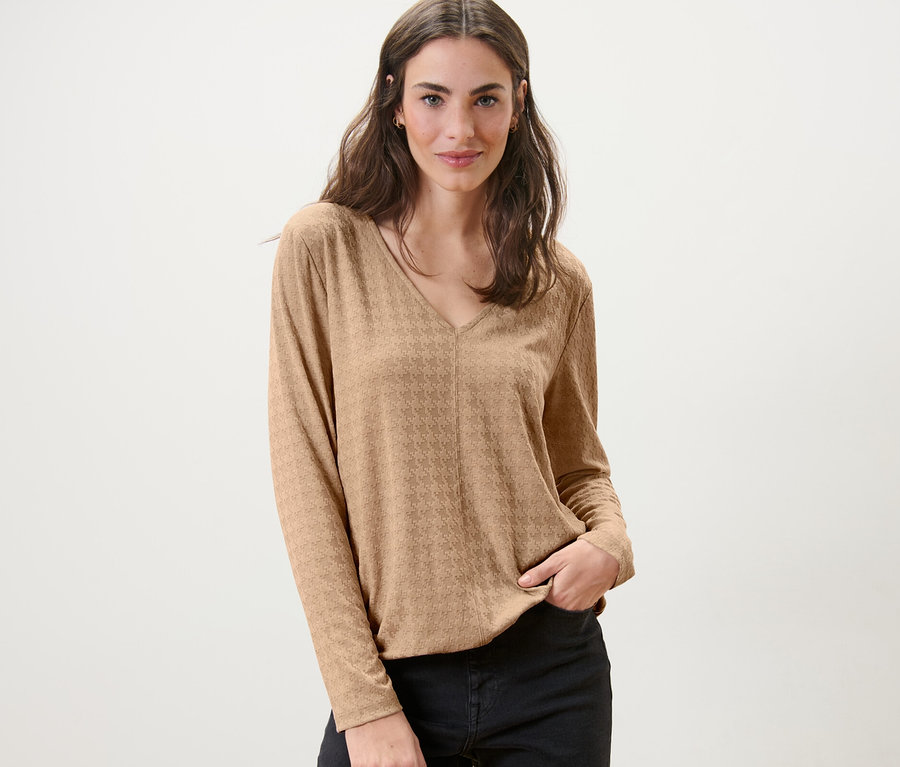 Frau posiert in einem strukturierten Langarmshirt, camel.