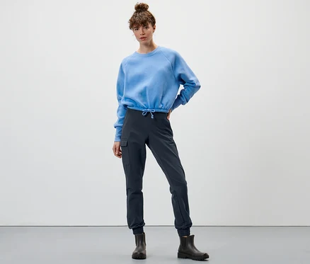 Frau posiert in blauem Sweatshirt und marineblauer Softshell-Joggpants.