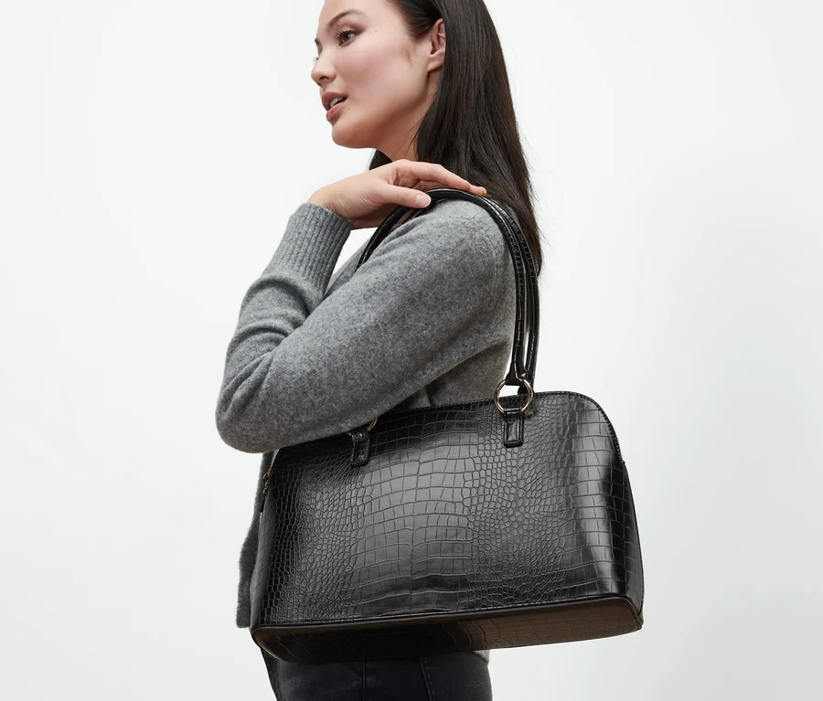 Frau mit schwarzem Shopper über der Schulter.