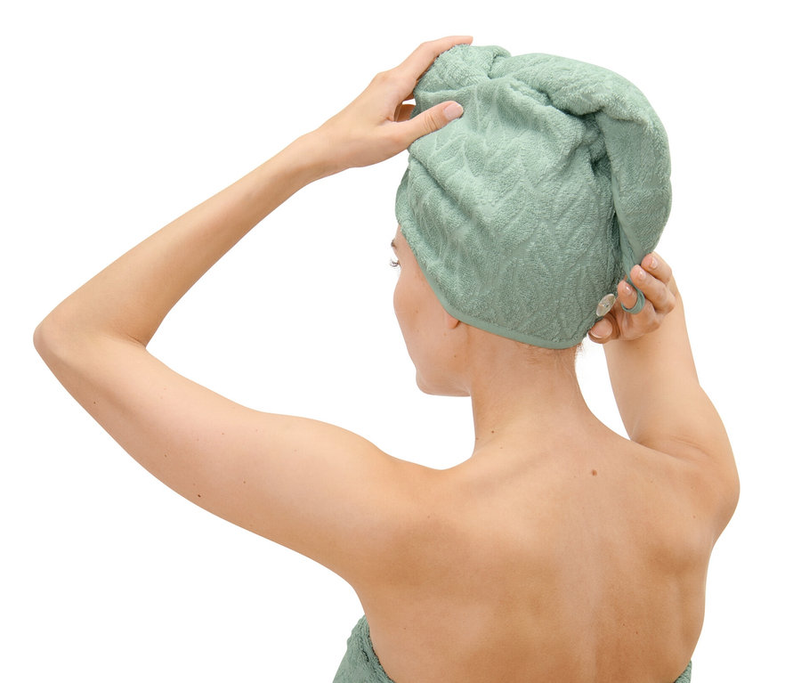 Frau befestigt ein Turban-Handtuch auf ihrem Kopf.
