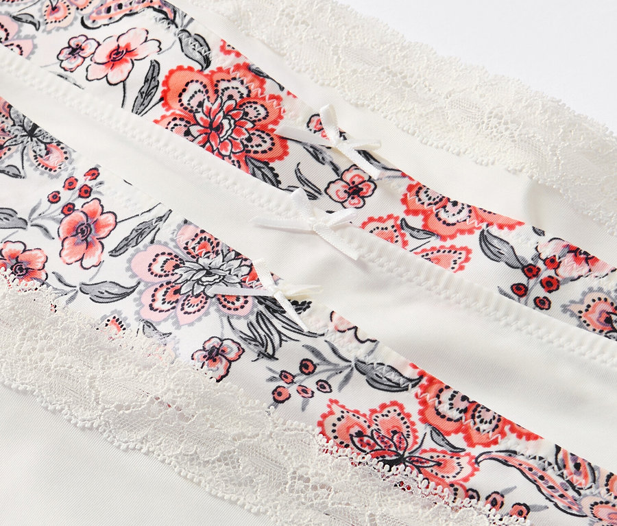 Nahaufnahme von 5 creme-farbenen Pantys mit Blumenmuster und Spitze.