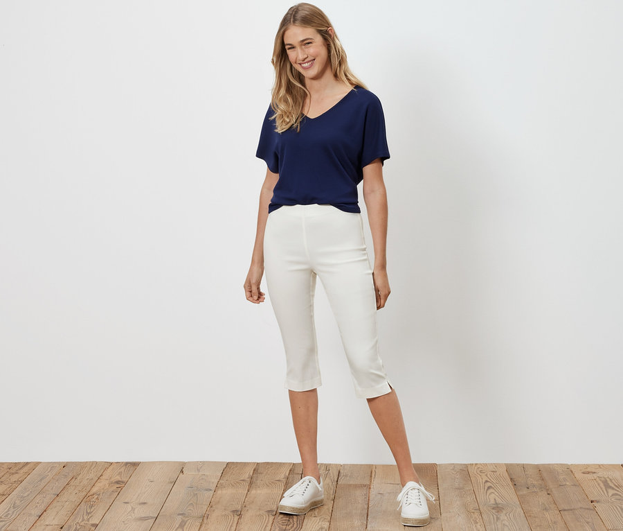 Frau posiert in weißer 3/4-Stretchhose.