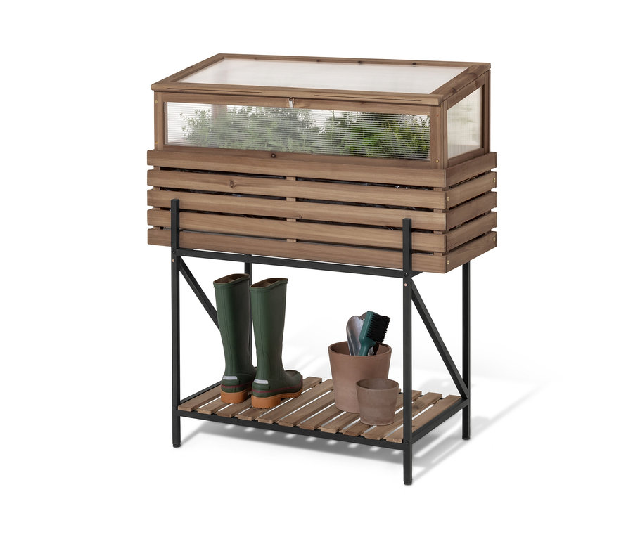 Ein Hochbeet mit Frühbeetaufsatz »Elin« steht auf einem schwarzen Regal. Auf dem Regal stehen grüne Gummistiefel und Blumentöpfe.