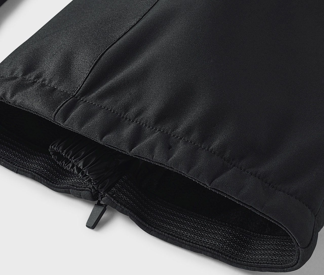 Detail einer schwarzen Hose mit Reißverschluss und elastischem Saum.