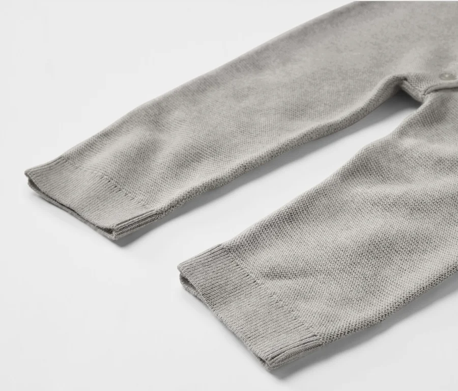 Detailansicht eines grauen Baby-Strickoveralls.
