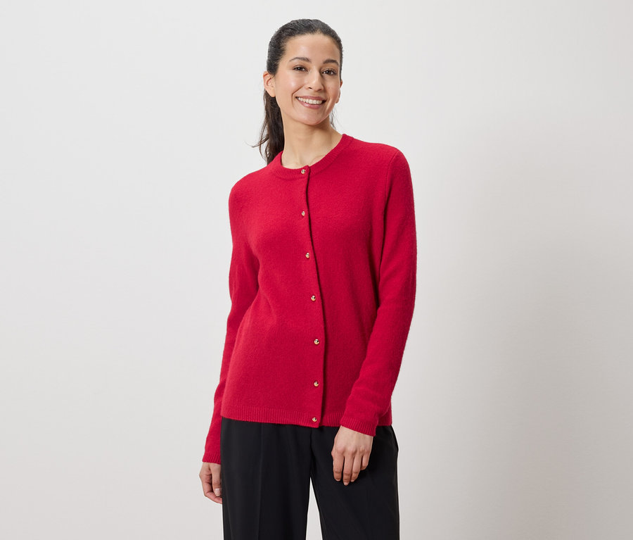 Frau trägt eine rote Strickjacke und eine schwarze Hose.