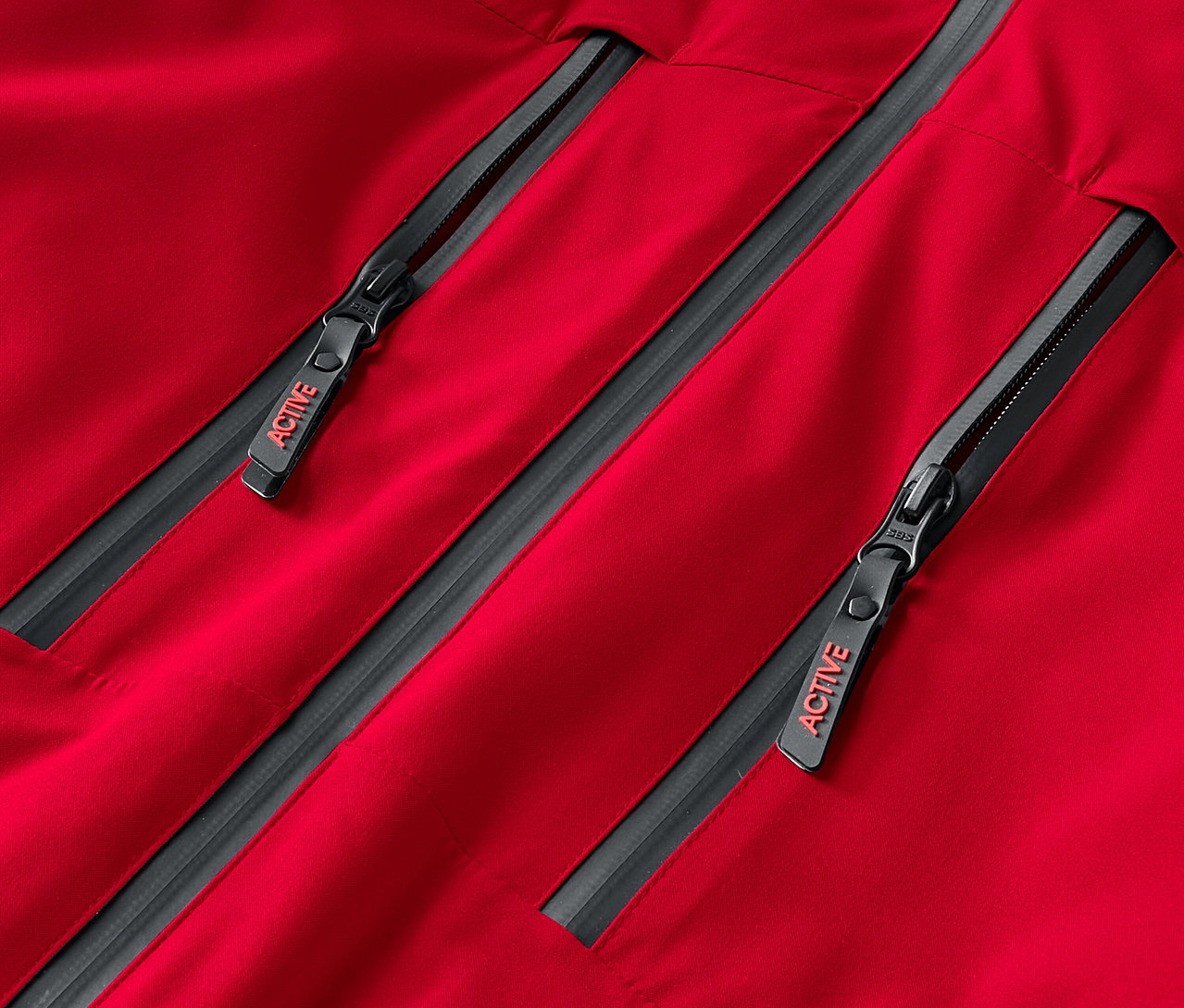 Detailaufnahme einer roten Jacke mit zwei grauen Reißverschlüssen, die die Aufschrift ACTIVE tragen.