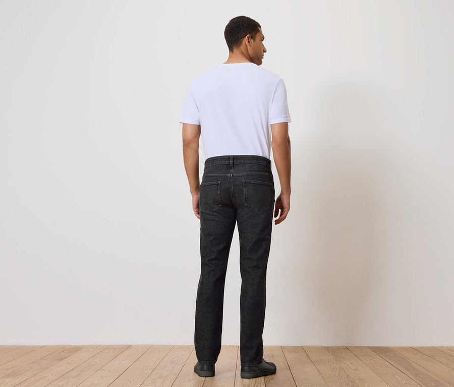 Ein Mann mit dem Rücken zur Kamera trägt Jeans und ein T-Shirt.