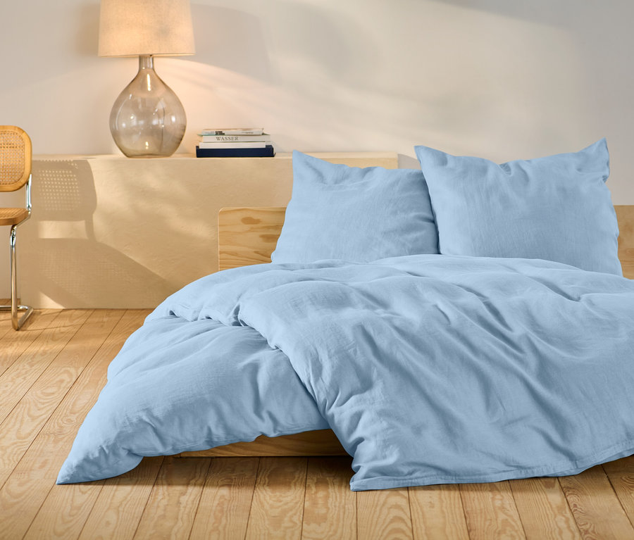 Helles blaues Leinen-Bettwäsche-Set in Standardgröße auf einem Bett.