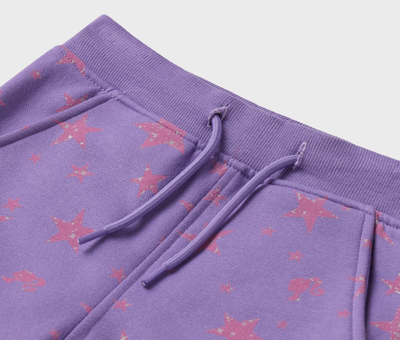 Detailaufnahme einer lila Jogginghose mit rosa Sternmuster und Kordelzug.