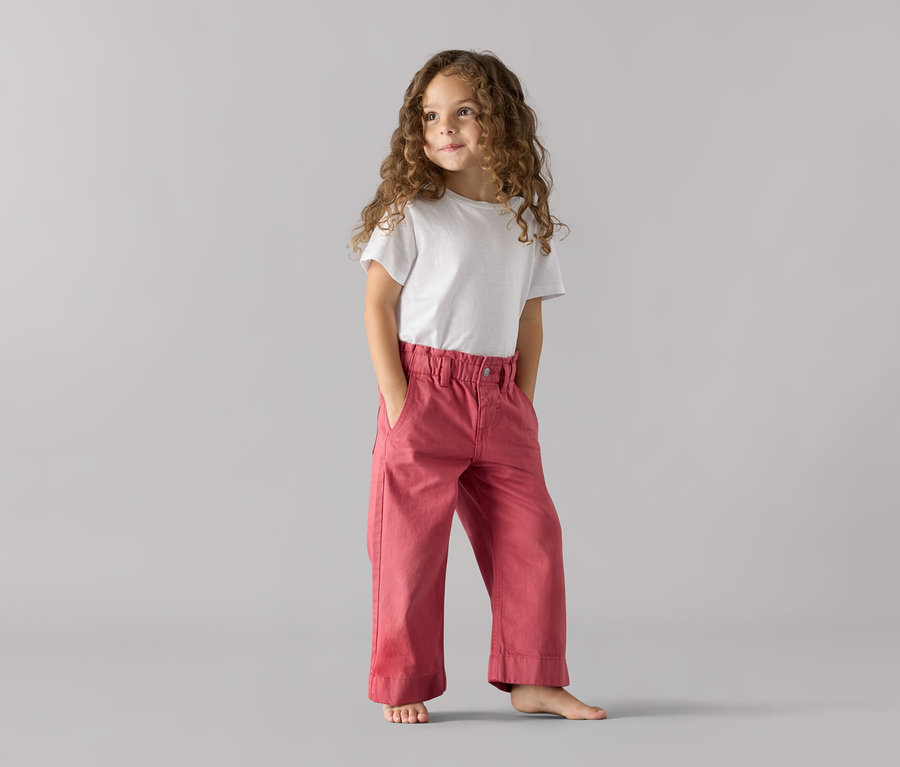 Mädchen steht mit Händen in den Taschen einer Kinder-Jeans – Fit »Greta«.