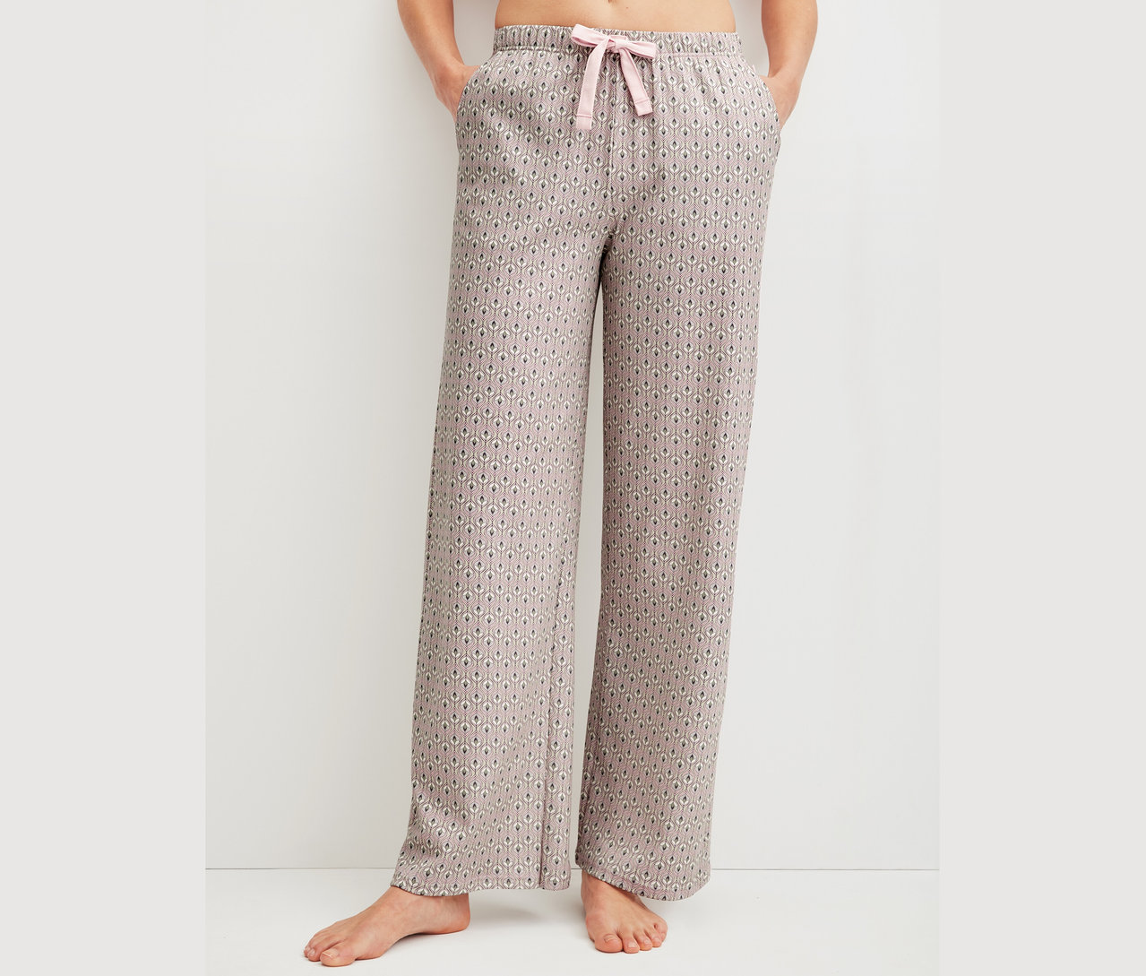 Frau trägt gemusterte Pyjamahose mit rosa Kordelzug.