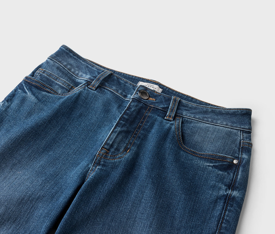 Nahaufnahme einer Jeanshose in dunklem Denim mit Taschen und Knopfdetail.