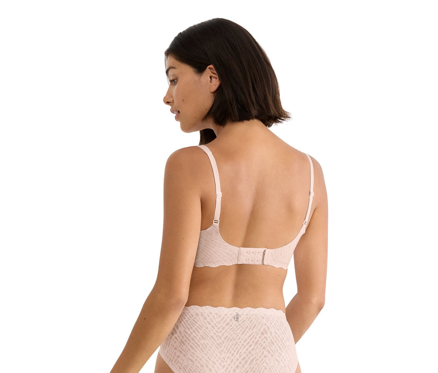 Frau von hinten, trägt einen hellrosa BH und passenden Slip mit Muster.