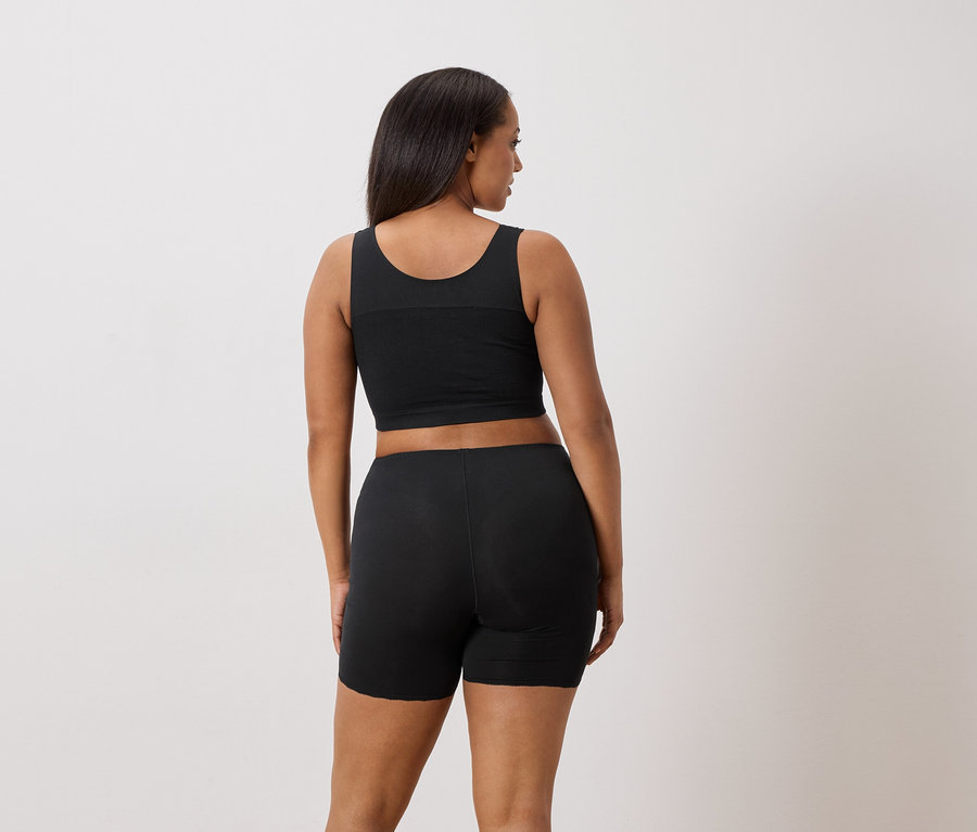 Frau von hinten, trägt ein schwarzes Tanktop und Shorts.