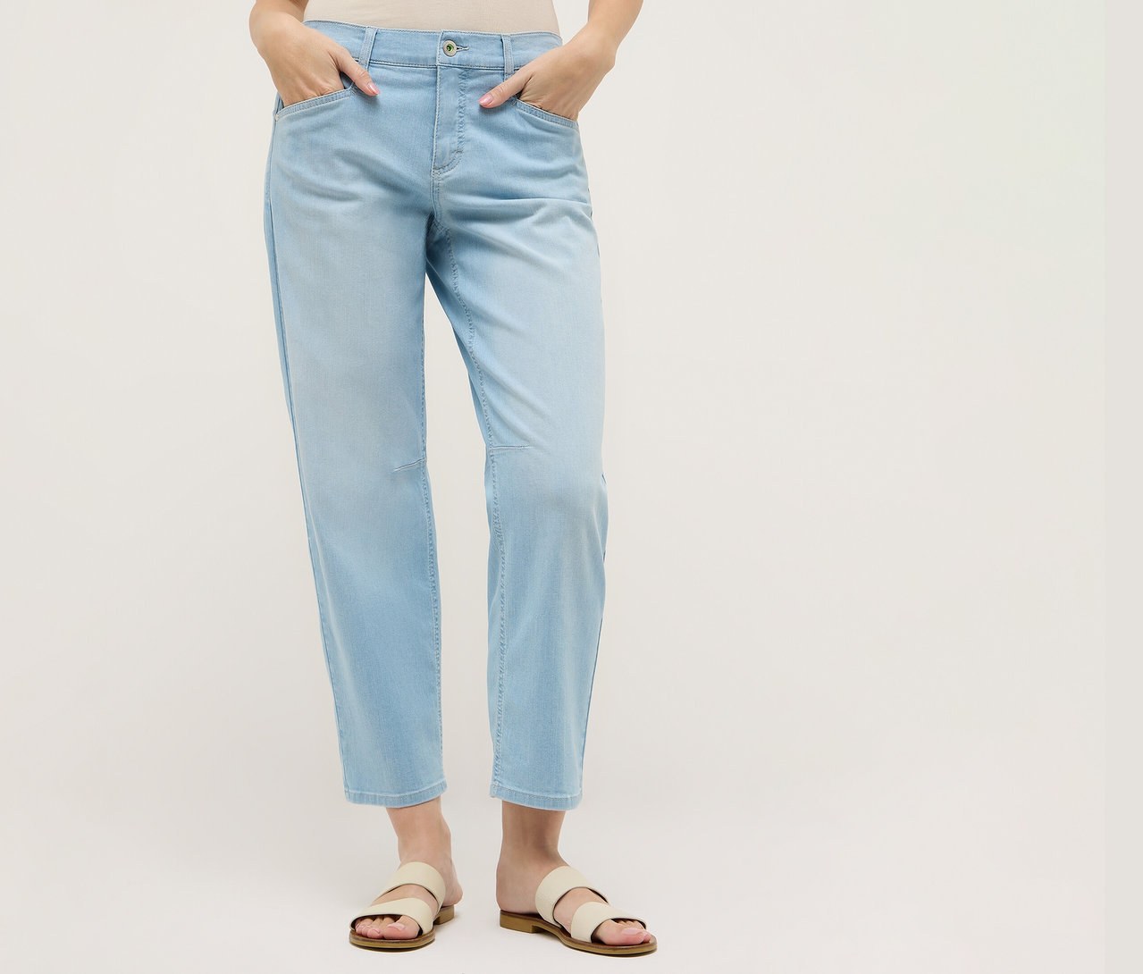 Frau mit Angels Denim »Evy Cool« O-Shape in Hellblau und Sandalen. Ihre Hände stecken in den Hosentaschen.