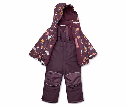 Lila Kinder-Schneeanzug und Jacke mit Einhorn-, Stern- und Regenbogenmuster liegen auf dem Boden.