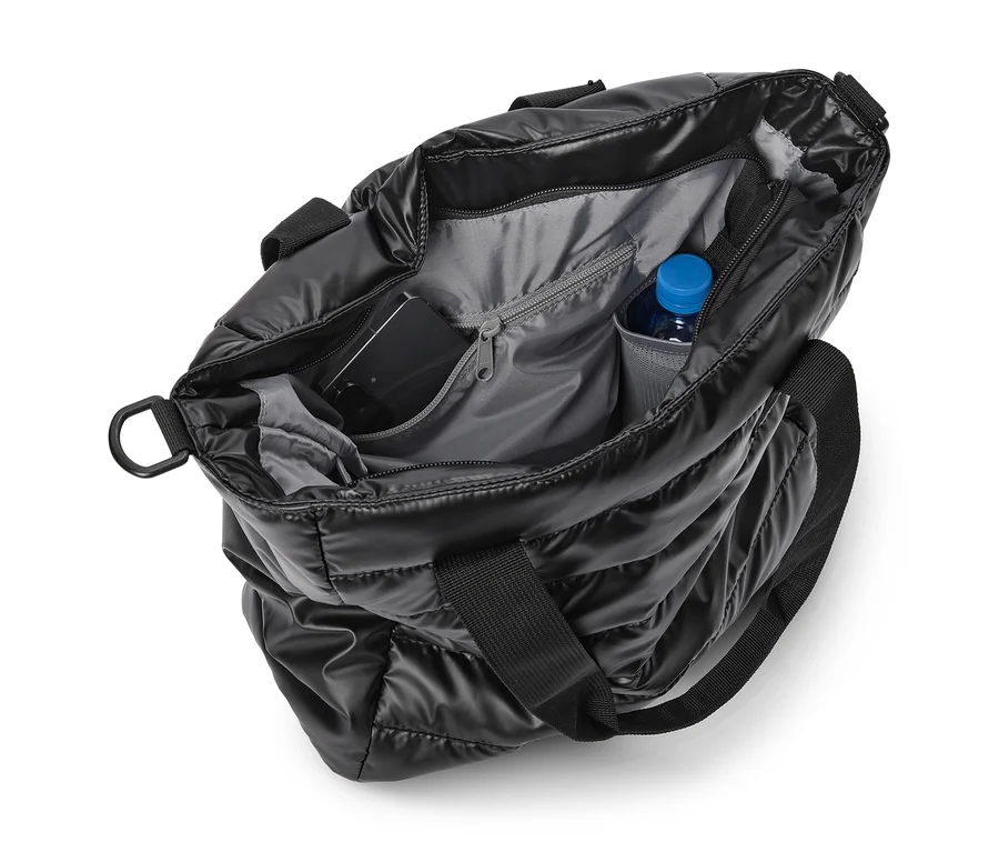 Offene schwarze gesteppte Tragetasche mit grauem Innenfutter, in der sich ein Smartphone und eine Wasserflasche mit blauem Verschluss befinden.