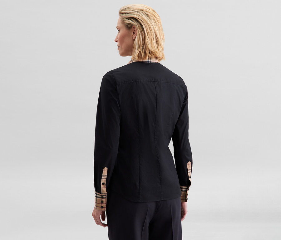 Frau von hinten, trägt eine schwarze Seidensticker Popeline-Bluse mit Karodetails an den umgeschlagenen Manschetten und am Kragen.
