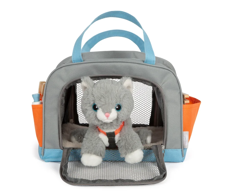Eine graue Stoffkatze sitzt in einer grauen Tasche mit blauen Griffen und orangefarbenen Seitentaschen, es handelt sich um die small foot Katze mit Tasche und Pflege-Set.