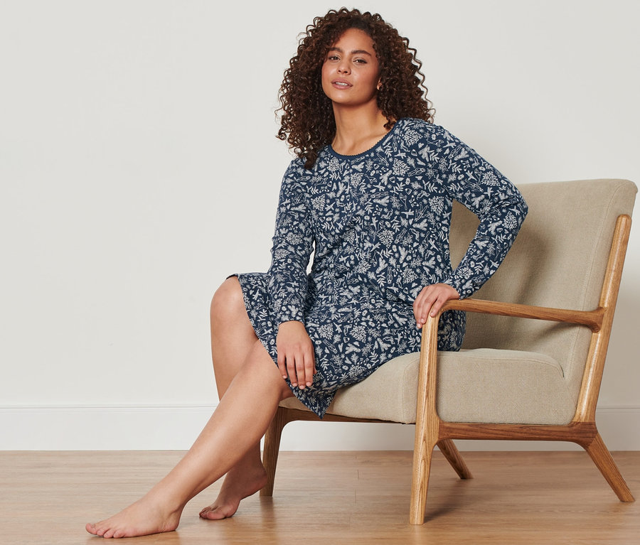 Eine Frau sitzt in einem Sessel und trägt ein blaues Nachthemd.