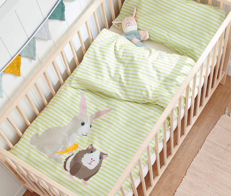Kinder-Renforcé-Bettwäsche mit Hasen- und Meerschweinchenmotiv in einem Holzbettchen.
