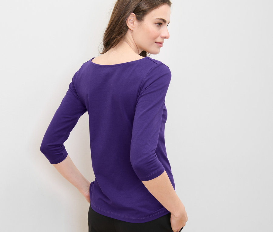 Frau posiert in lila Shirt mit 3/4-Arm.