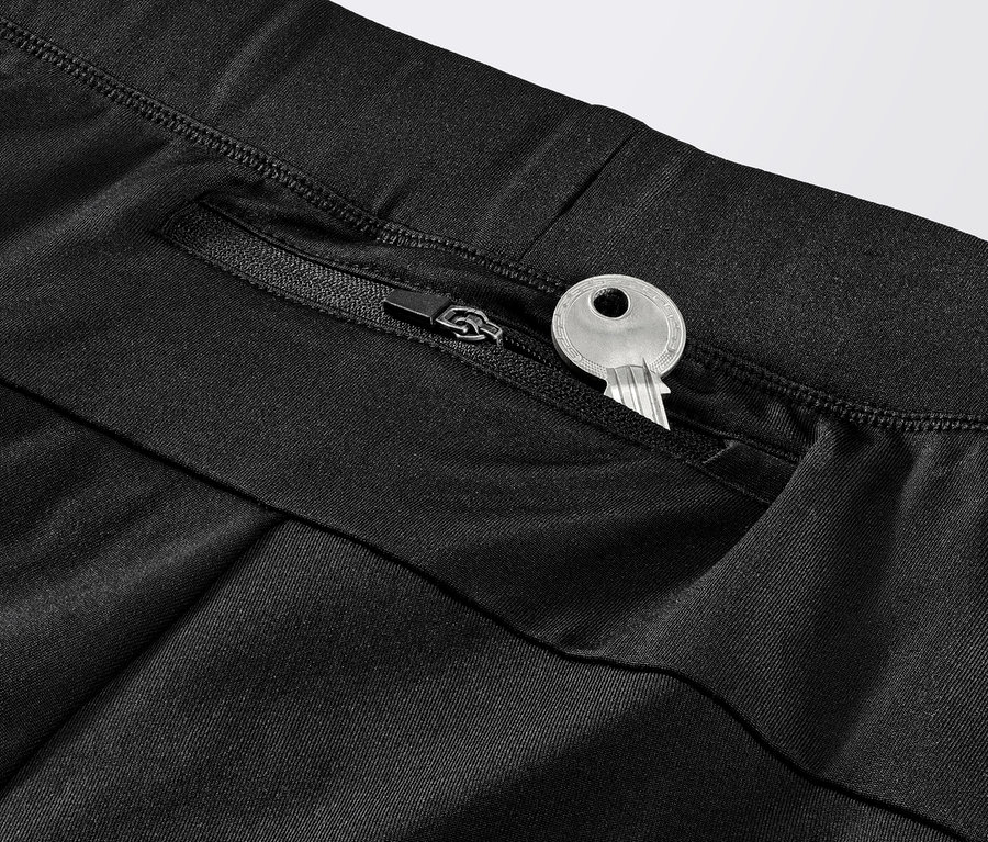 Detailaufnahme einer schwarzen Windprotection-Lauftight mit einem Schlüssel in der Reißverschlusstasche.