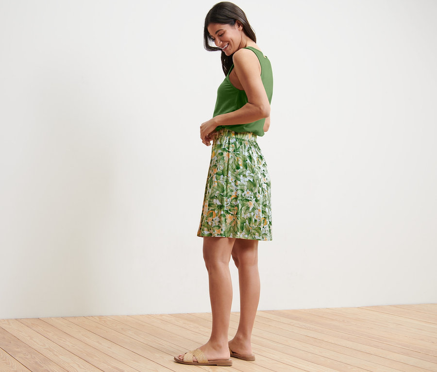 Seitenansicht einer Frau in grünem Top und bedrucktem Jerseyrock.