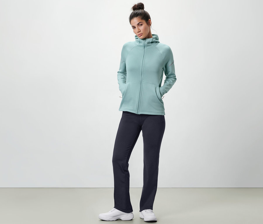 Frau posiert in blauer Thermohose und hellblauem Kapuzenpullover.