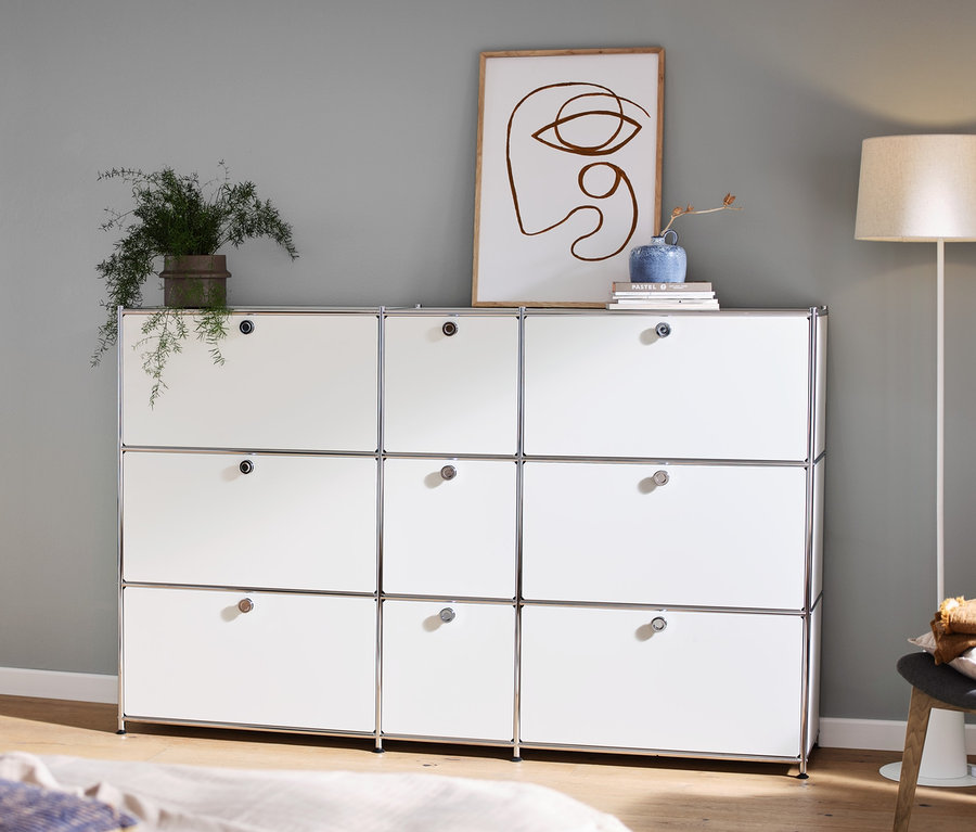 Im Zimmer stehen eine weiße Kommode »CN3« mit 9 Klappen, auf der Deko steht, links ein Konsolentisch und eine Stehleuchte mit Textilschirm.