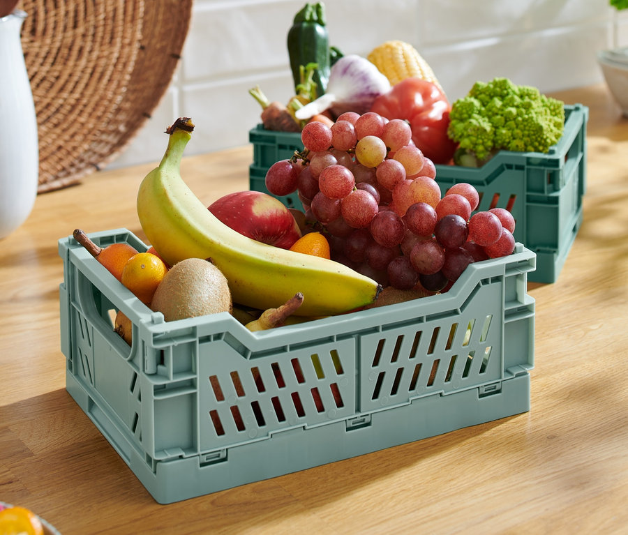 Zwei klappbare Ordnungskisten gefüllt mit Obst und Gemüse auf einer Holzplatte.