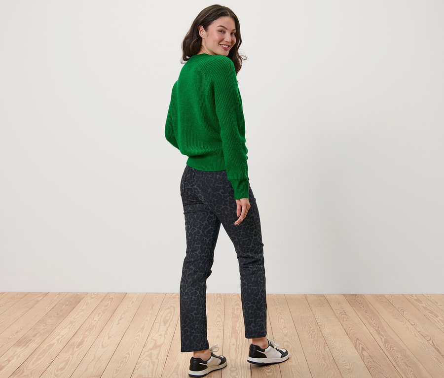 Eine Frau blickt über die Schulter und trägt einen grünen Pullover und eine bedruckte Straight Jeans – Fit »Kira«.