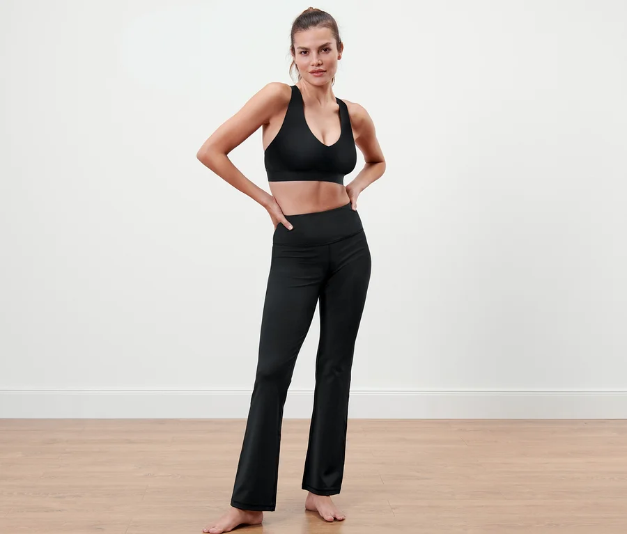 Frau posiert in schwarzem Sport-BH und einer Bodyforming-Sporthose.